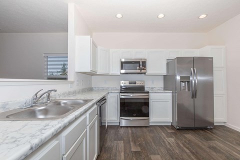 a white kitchen with stainless steel appliances and marble counter tops