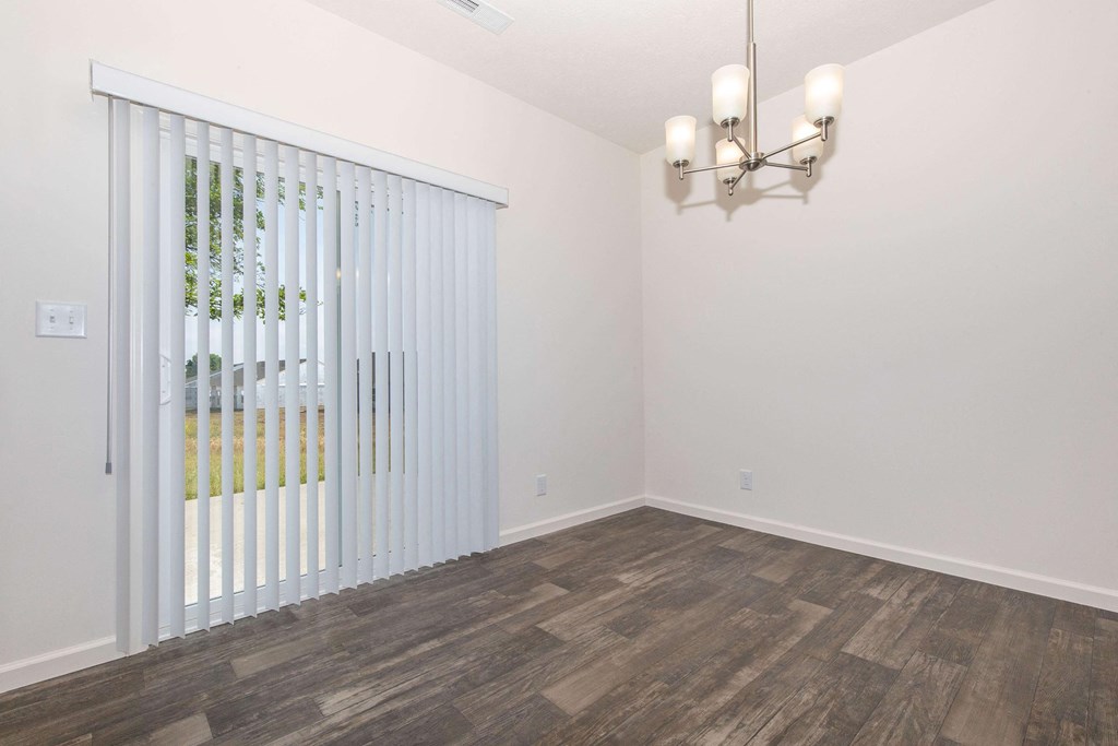 an empty living room with white walls and wood flooring and a white blinds