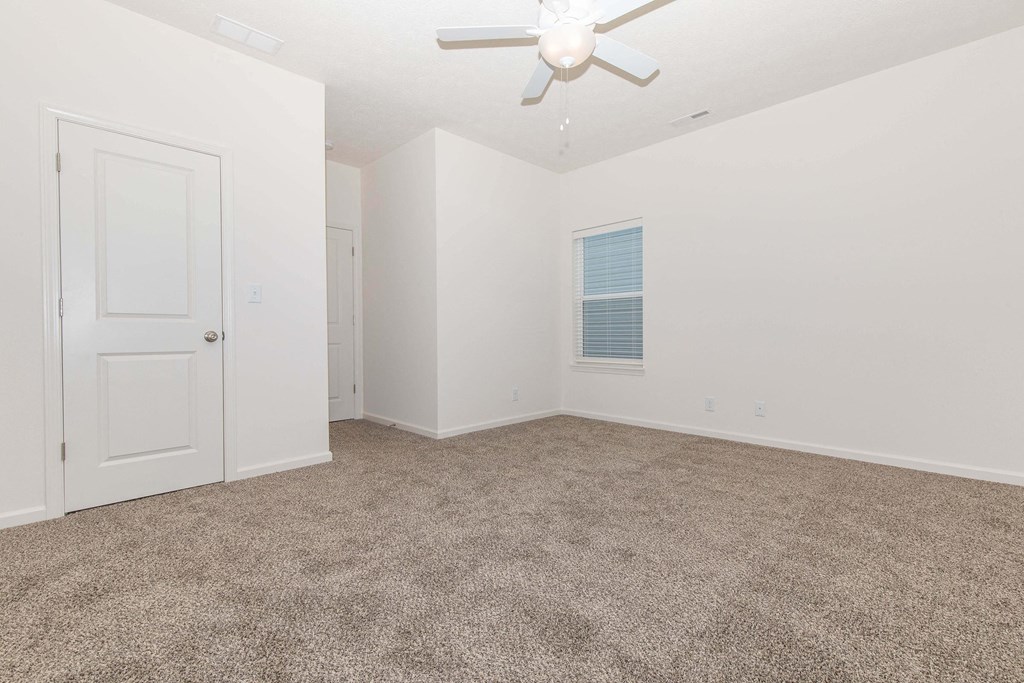an empty room with carpet and a ceiling fan