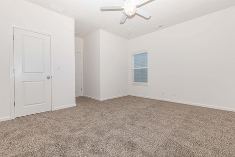 an empty room with carpet and a ceiling fan