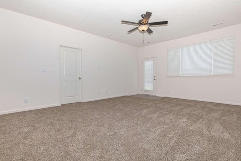the spacious living room has carpeting and a ceiling fan