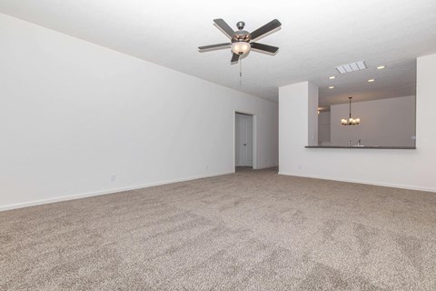 an empty living room with a ceiling fan and white walls
