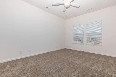 an empty room with carpet and a ceiling fan
