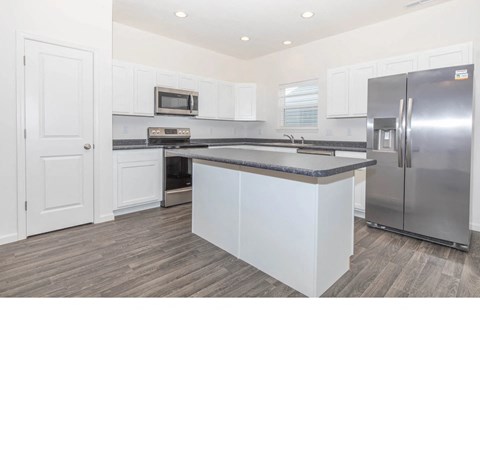 a kitchen with an island and stainless steel refrigerator