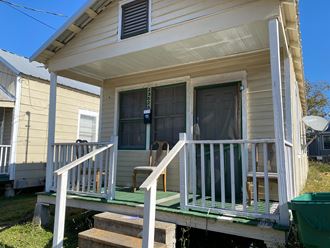the front porch of a yellow house with a porch swing