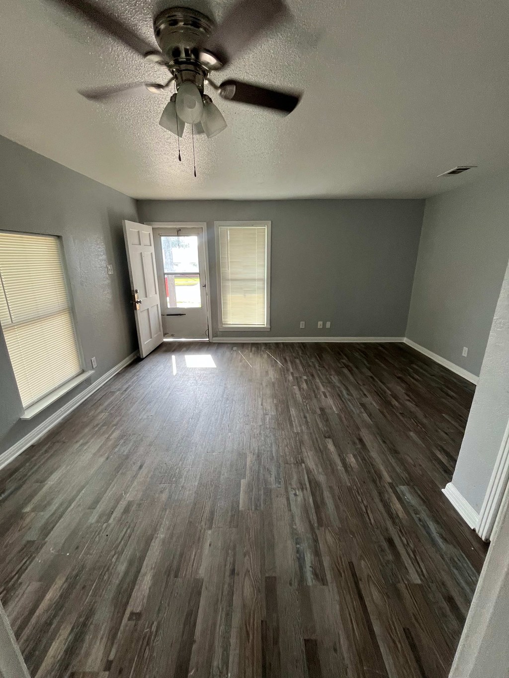 A room with a ceiling fan and wood flooring.
