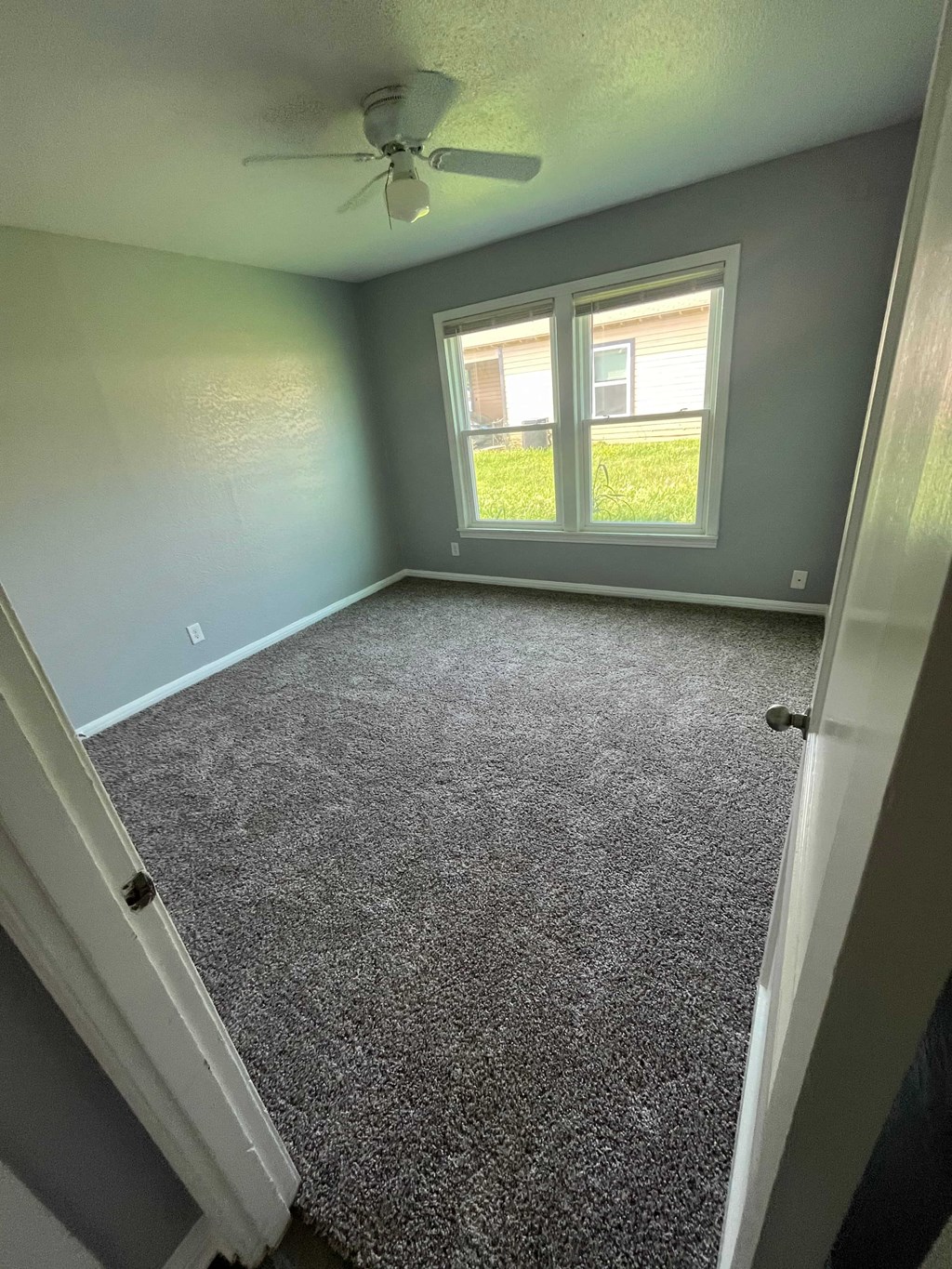 A room with a ceiling fan and a carpeted floor.