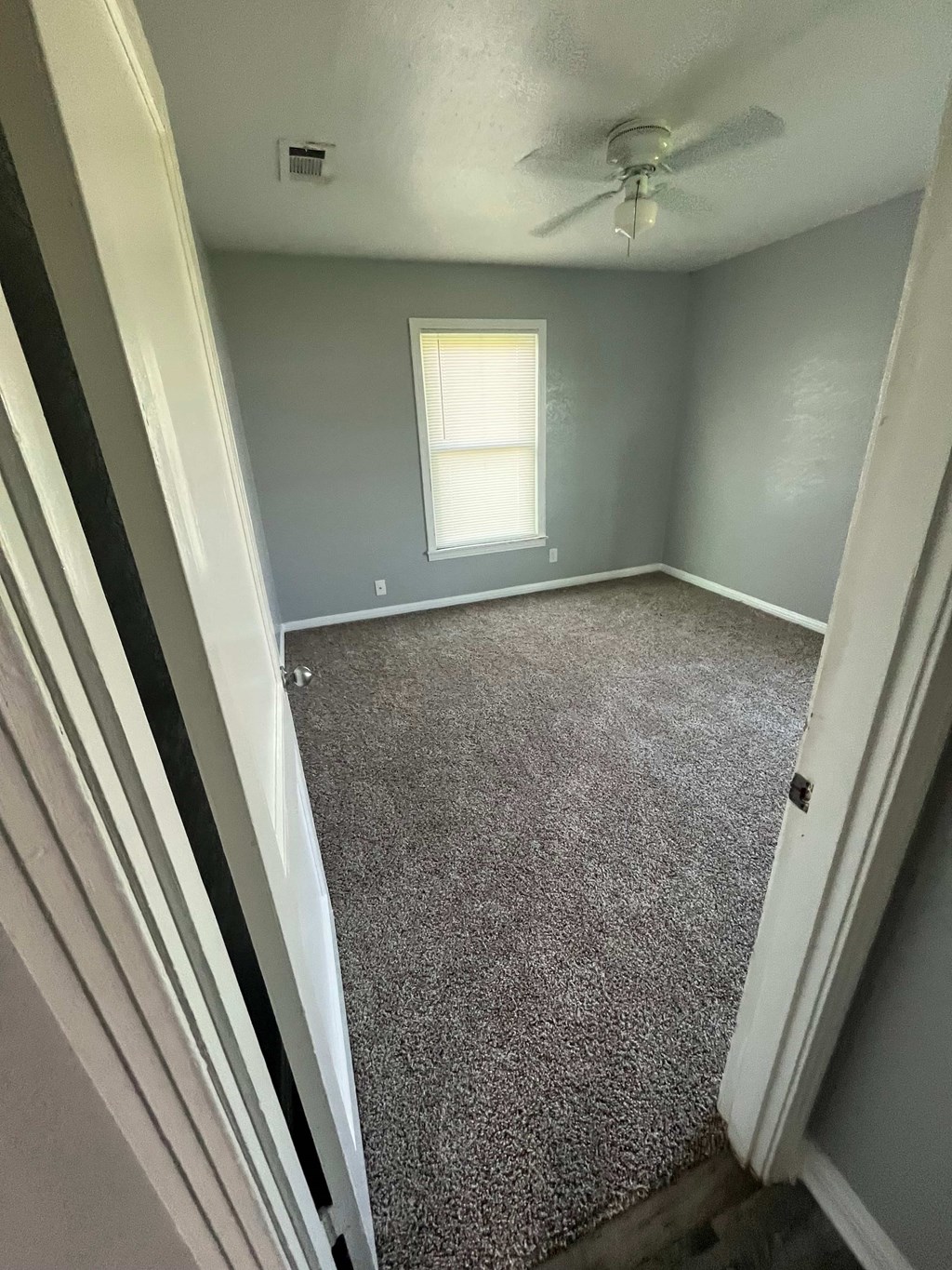 A room with a carpeted floor and a window.