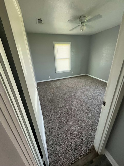 A room with a carpeted floor and a window.