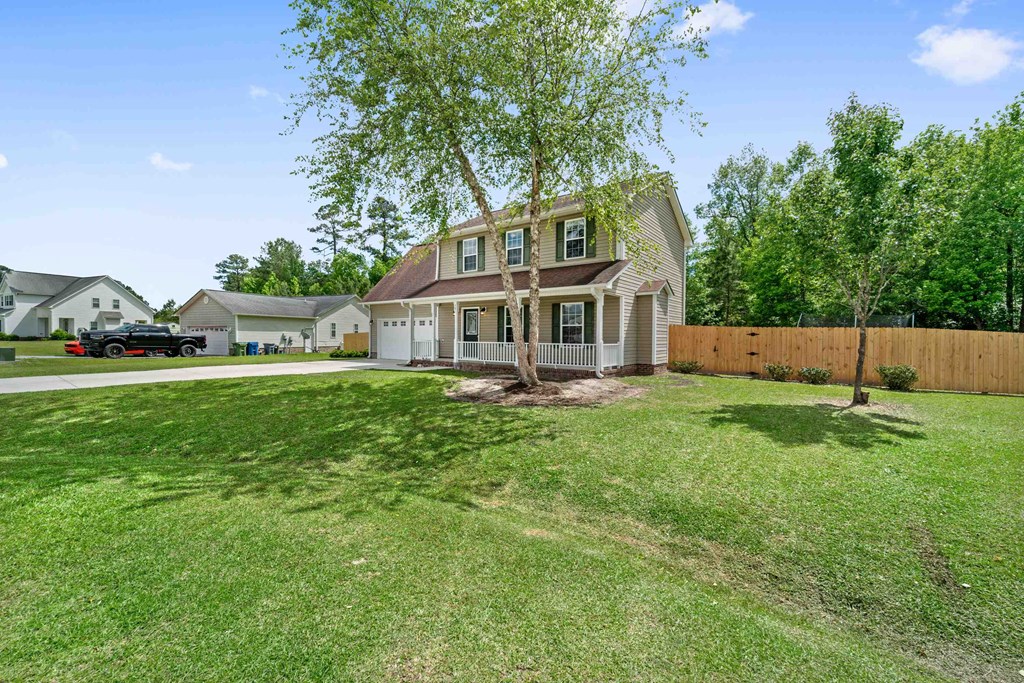 the front of a house with a yard and a tree