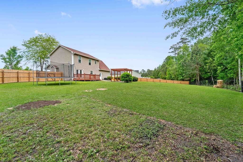 a backyard with a fence and a house in the background