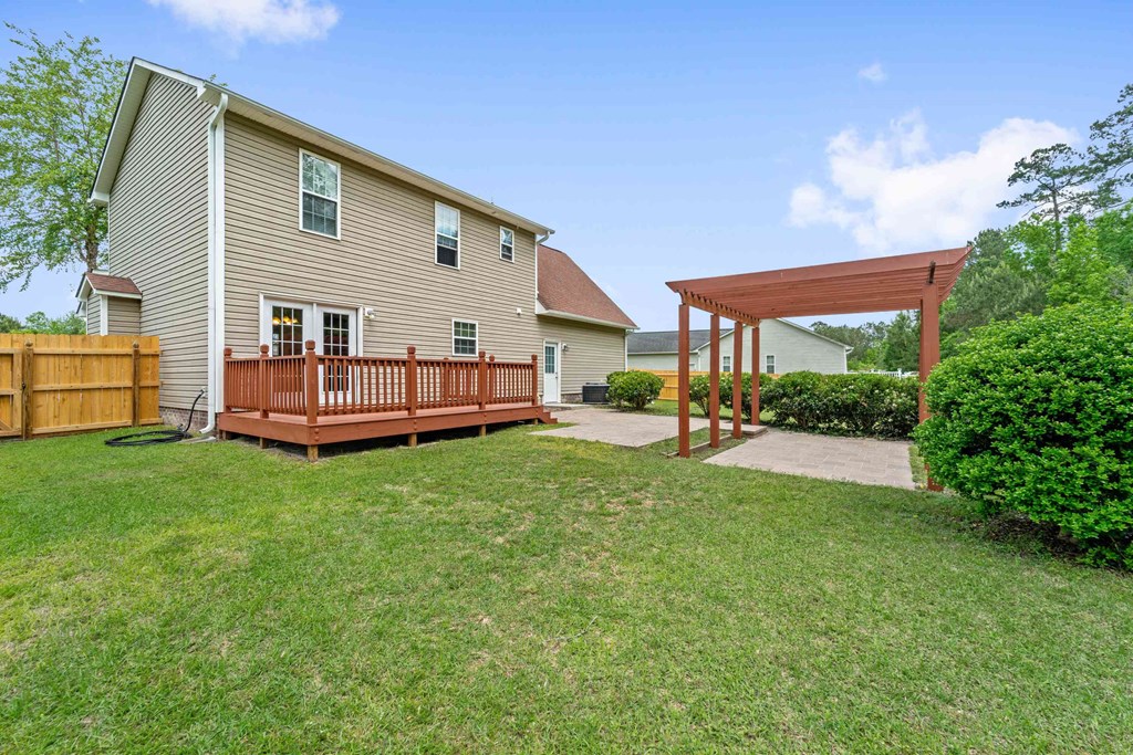 a backyard with a wooden deck and a house