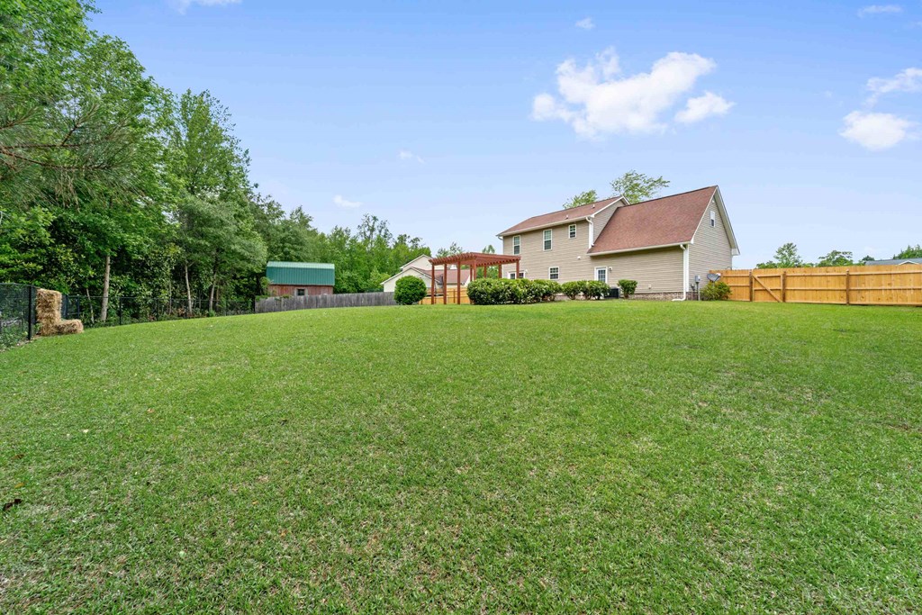 a yard with a house in the background and a fence