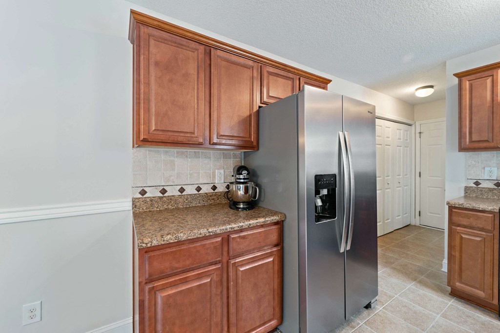 a kitchen with wooden cabinets and a stainless steel refrigerator