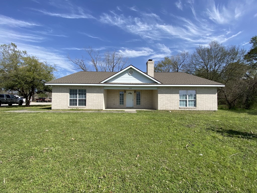 a small brick house with a grassy yard and a blue sky