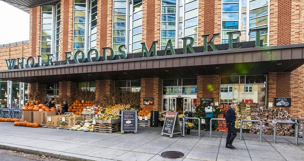 a man walking past a farmers market on a city street