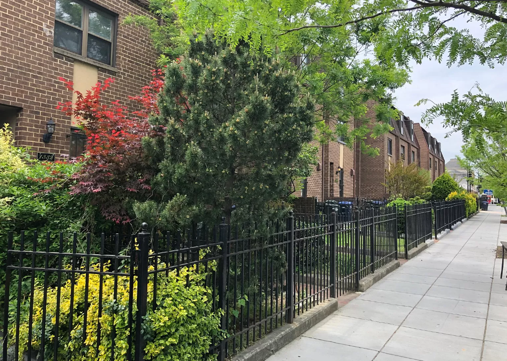 a sidewalk in front of a wrought iron fence