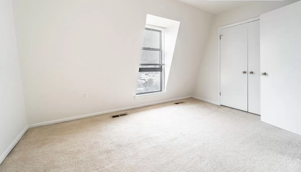 an empty room with a window and a closet