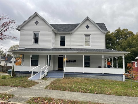 the front of a white house with a porch