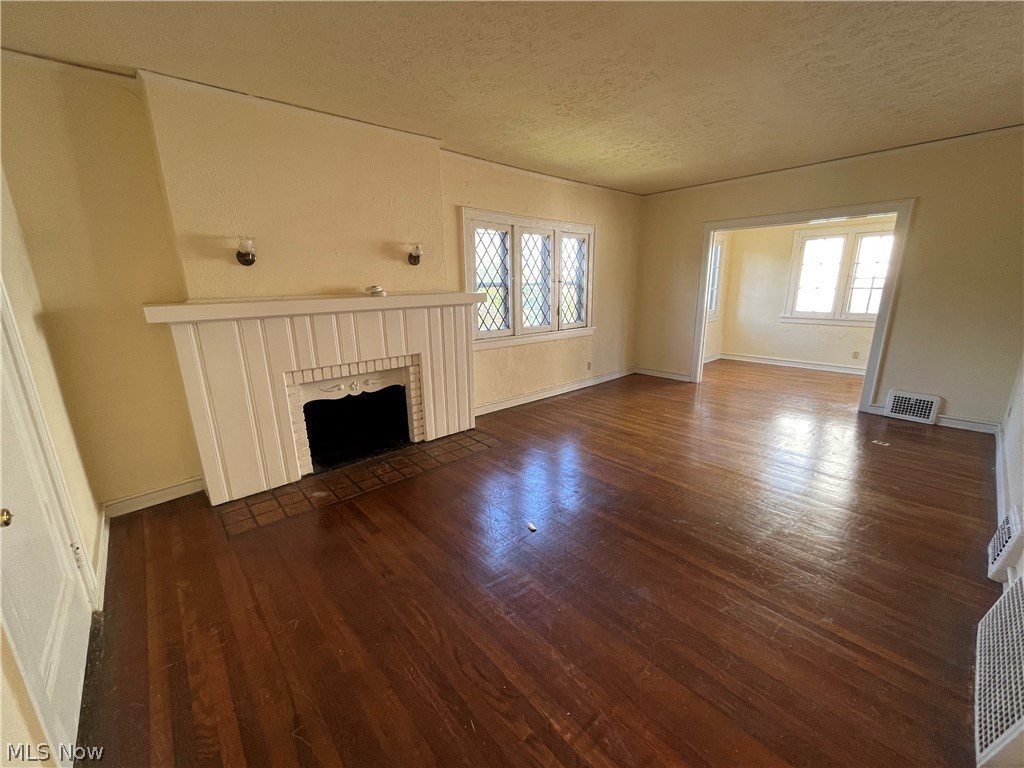 an empty living room with a fireplace and wooden floors