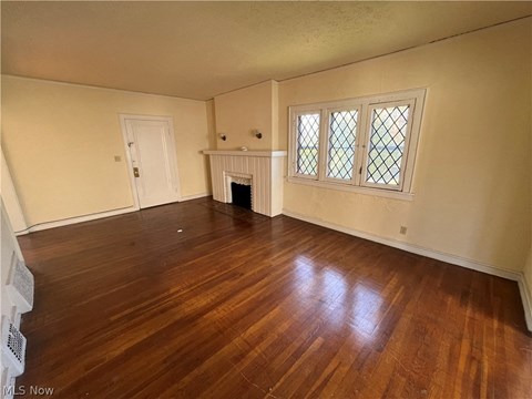 an empty living room with wood floors and a fireplace
