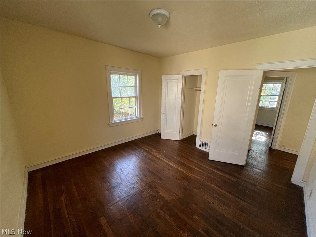 an empty living room with hard wood floors and a window