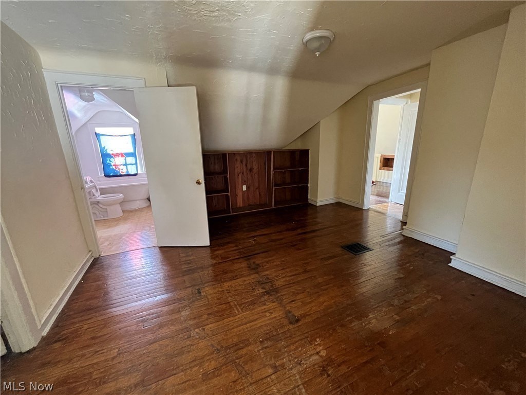 an empty living room with wooden floors and a bathroom