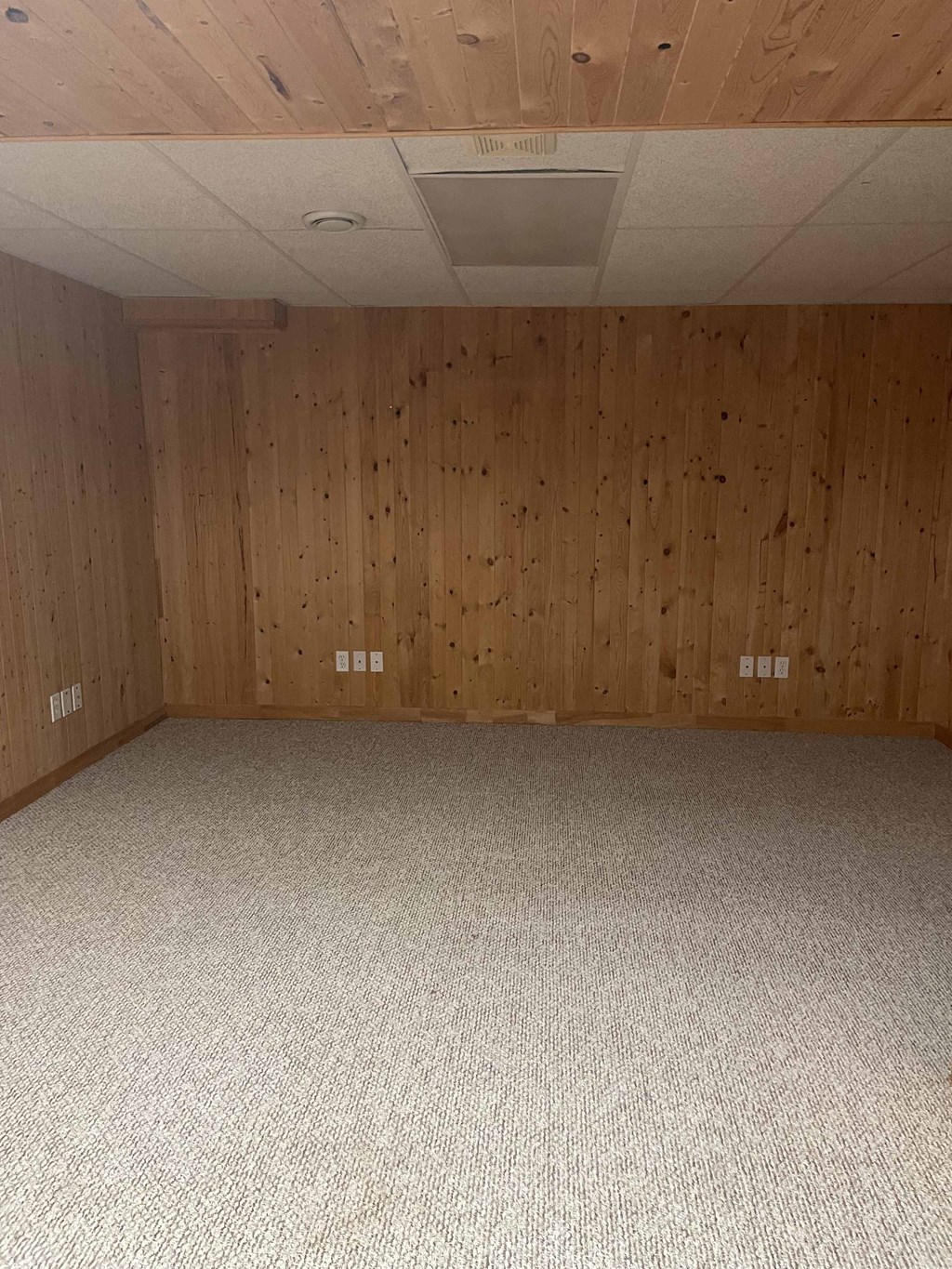 an empty room with wood paneled walls and a carpeted floor