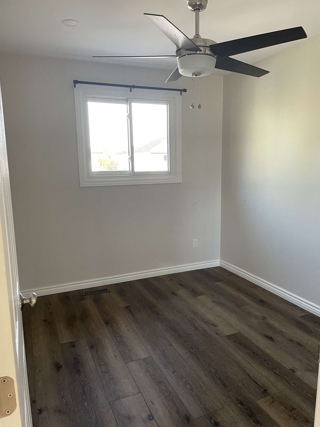 an empty room with a ceiling fan and a window
