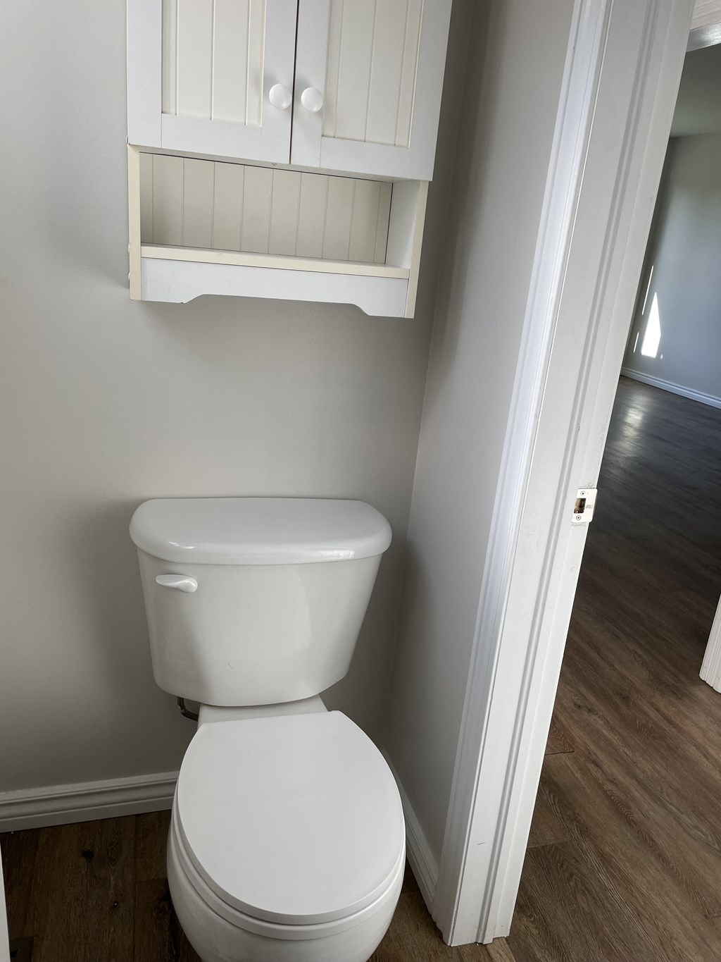 a small bathroom with a toilet and a cabinet above it