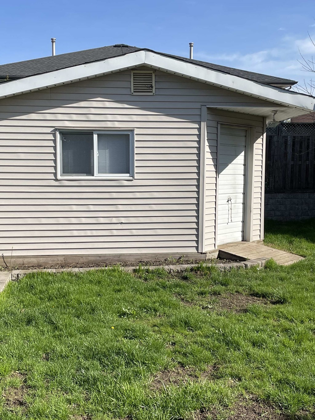the side of a house with a door and a grass yard