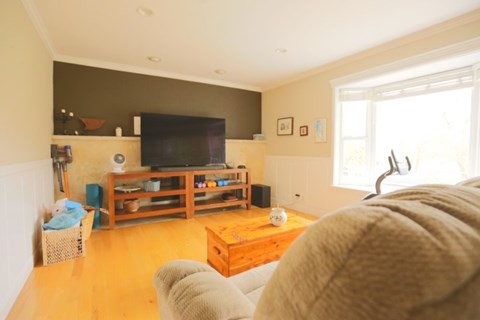 A living room with a television and a person sitting on a couch.
