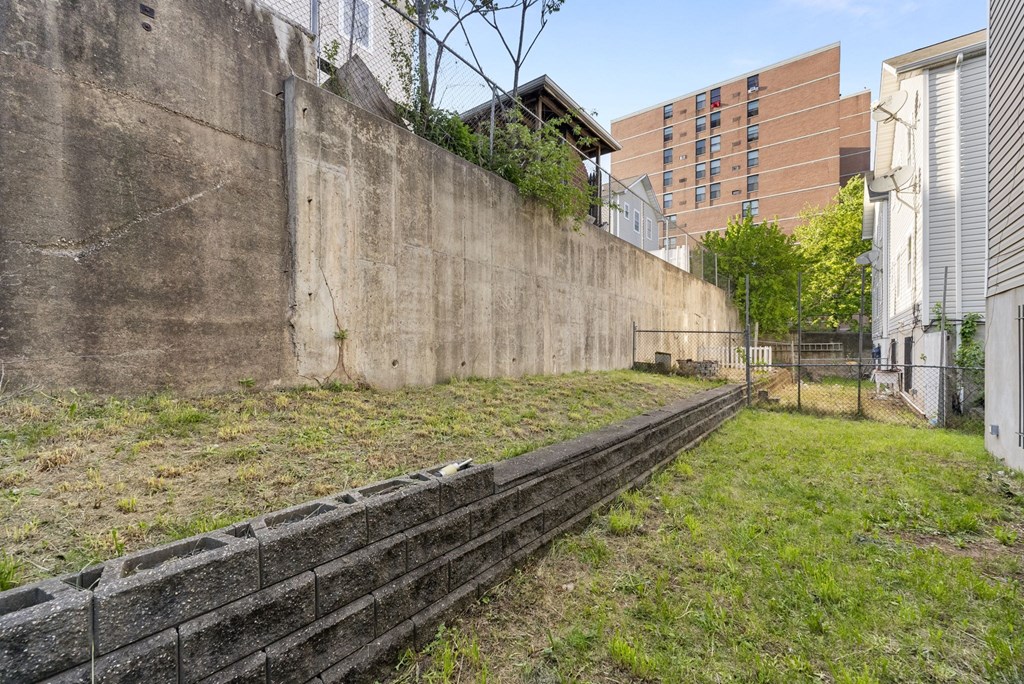 the retaining wall of a building with grass and a fence