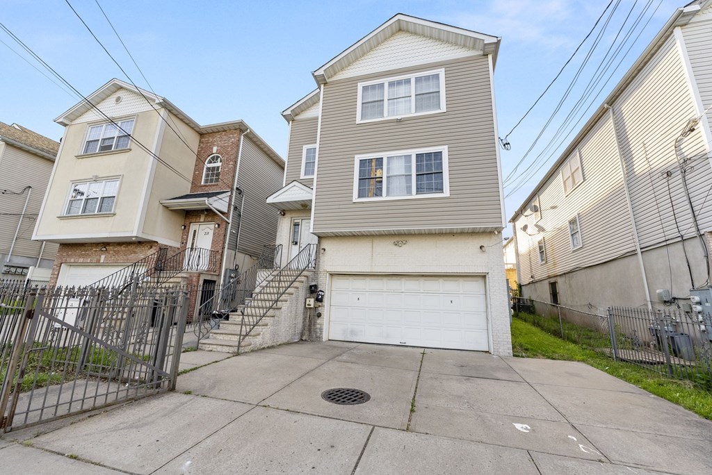 the front of a tan house with a white garage door