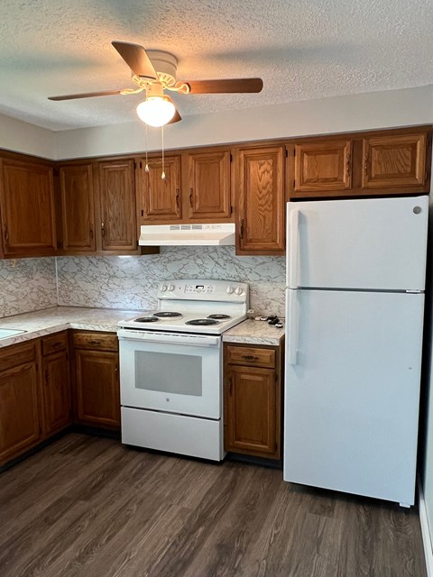 A kitchen with a white fridge, white stove and white oven.