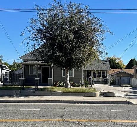 a house on the corner of a street with a tree