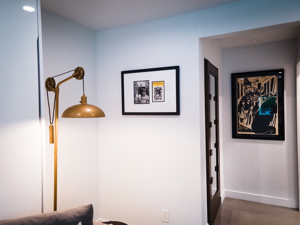 a living room with a lamp and pictures on the wall