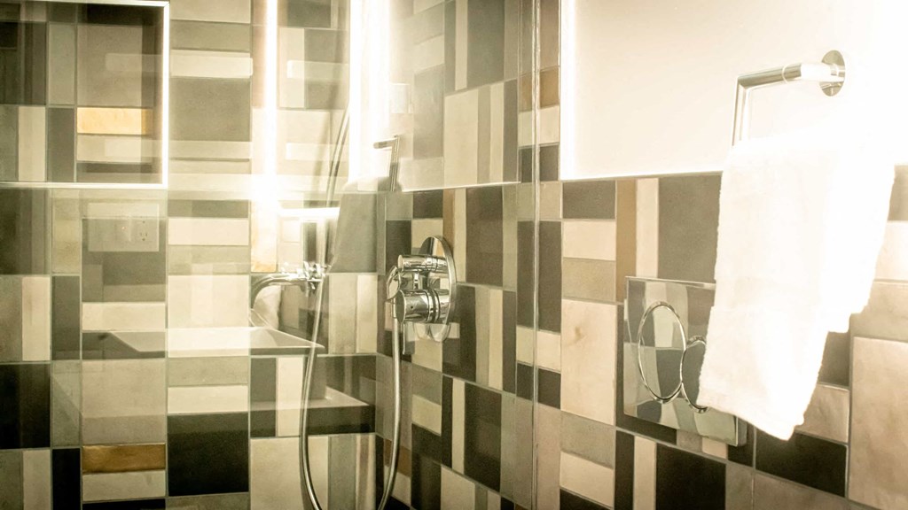 a white and black tiled bathroom with a shower and a towel