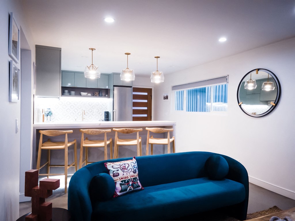 a living room with a blue couch in front of a kitchen