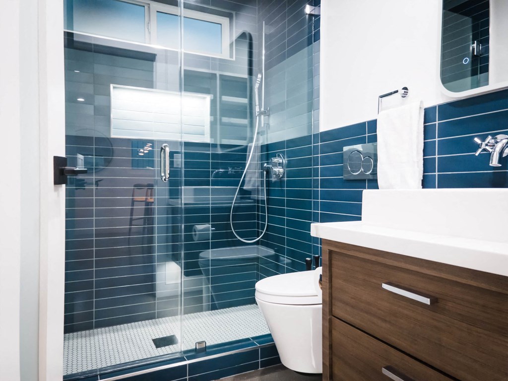 a bathroom with blue tiles and a shower and a toilet