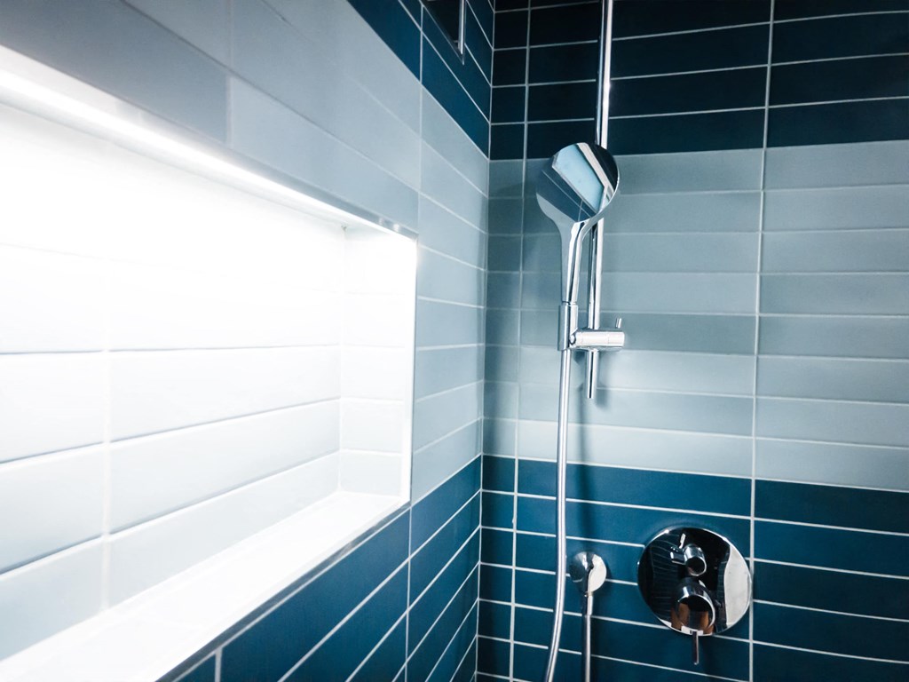 a blue tiled bathroom with a shower and a window