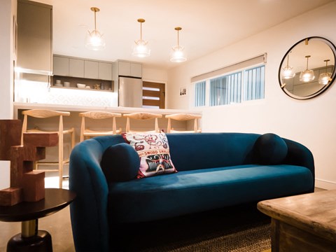 a living room with a blue couch and a kitchen in the background