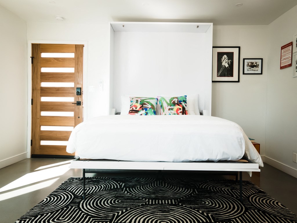 a bedroom with a white bed and a black and white rug