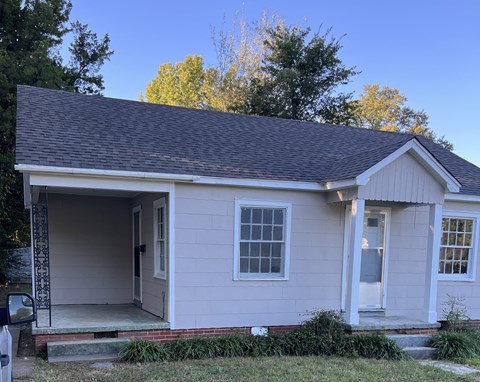 the front of a white house with a porch