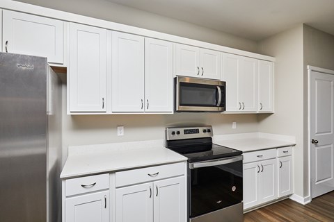 A kitchen with white cabinets and appliances.