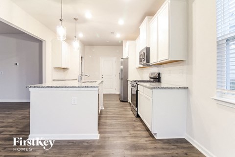 a white kitchen with white cabinets and a wood floor
