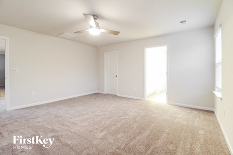 a spacious living room with white walls and a ceiling fan