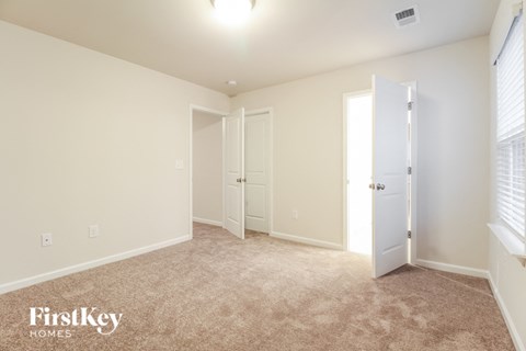 a bedroom with white walls and carpet and a door to a closet
