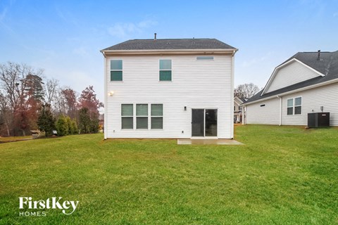 the back of a white house with a grassy yard