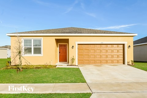 a yellow house with a garage door and a lawn